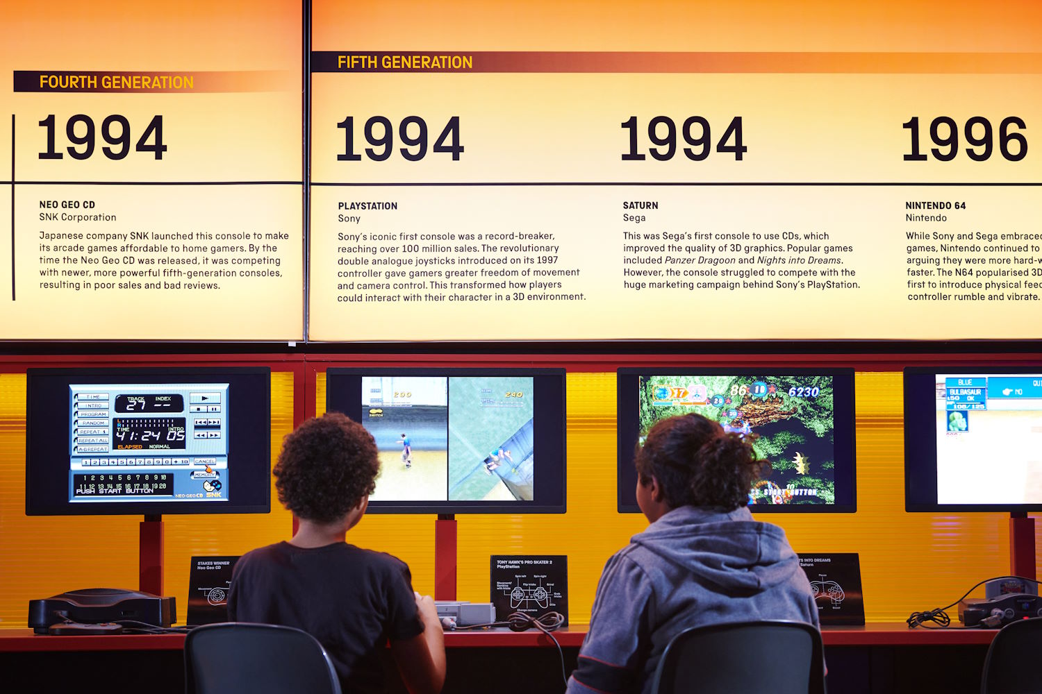 Kids sit in front of the timeline of video games from the Science Museum's Power Up exhibit